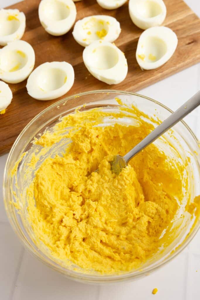 egg yolks mixed together with mayo, mustard, and other ingredients in a glass bowl. 