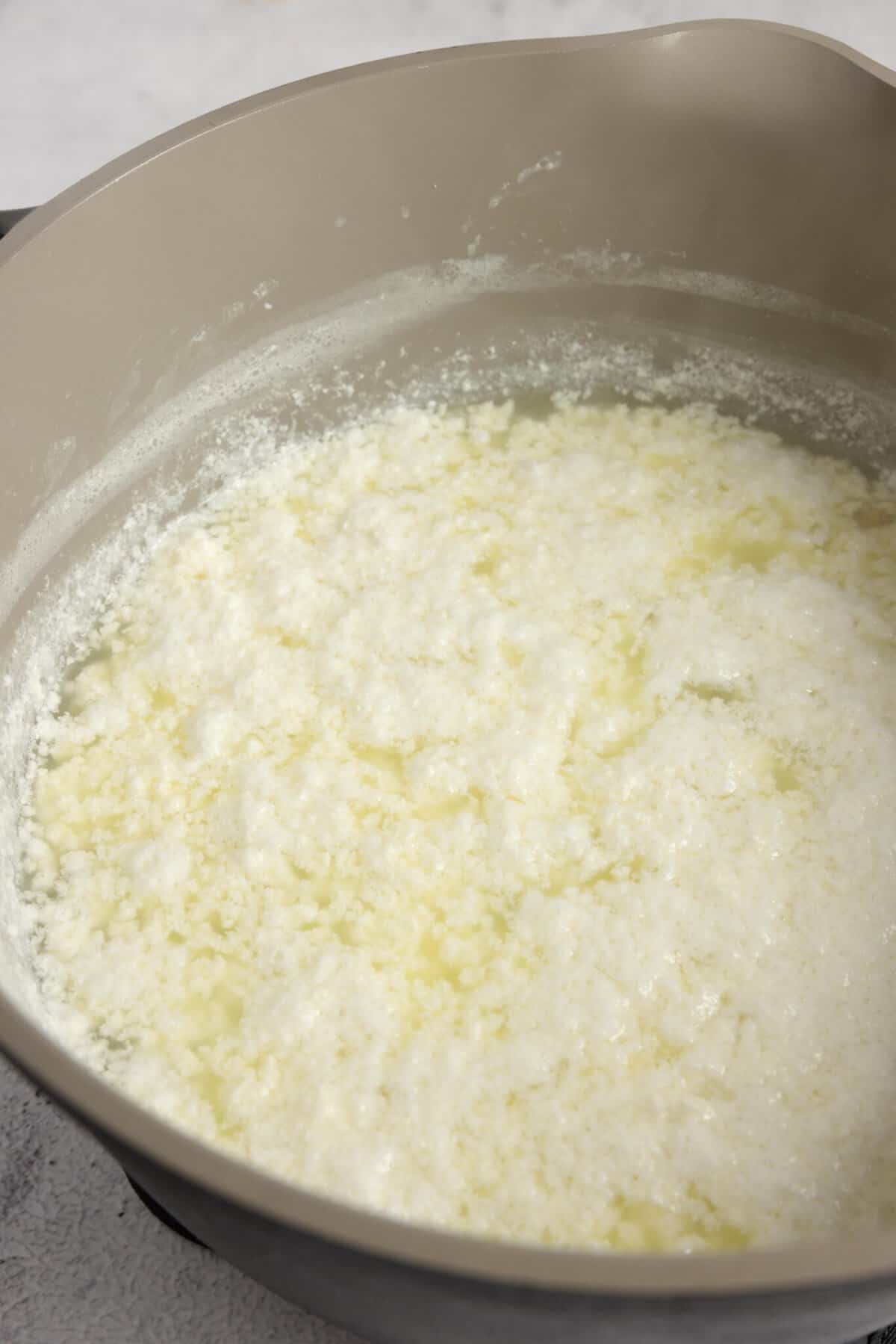 curds and whey separated in whole milk after begin heated in a gray pot