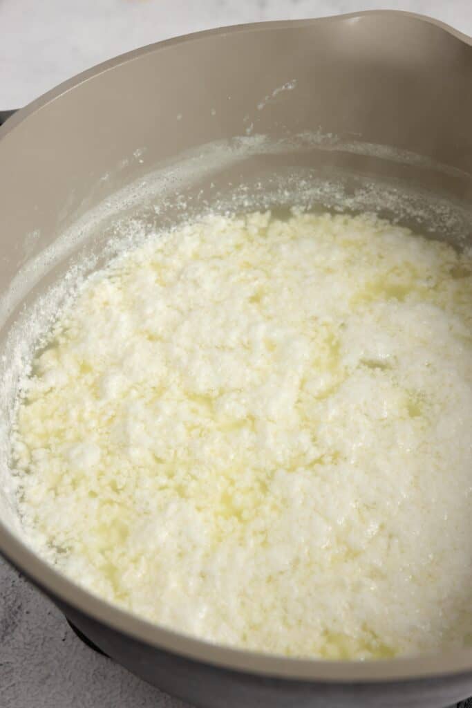 curds and whey separated in whole milk after begin heated in a gray pot