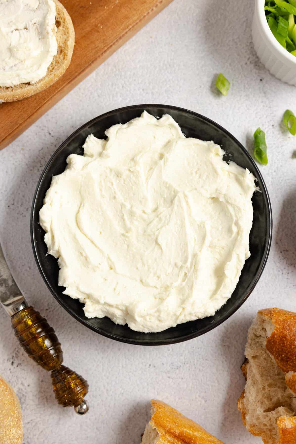 close up of homemade cream cheese in a black bowl on a white countertop