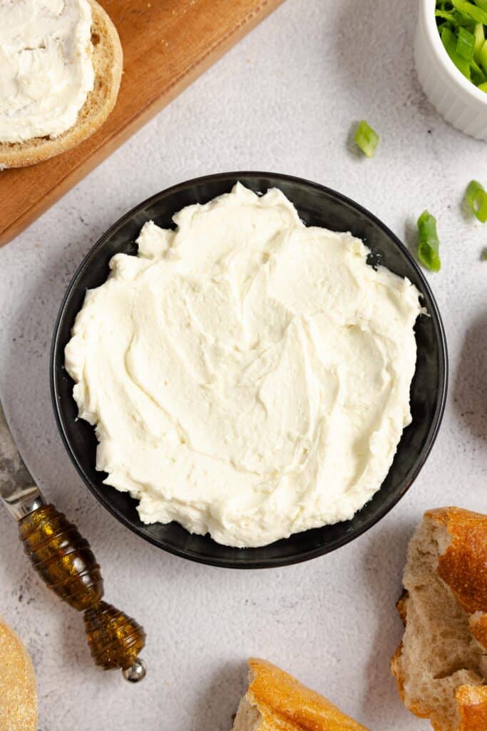 close up of homemade cream cheese in a black bowl on a white countertop