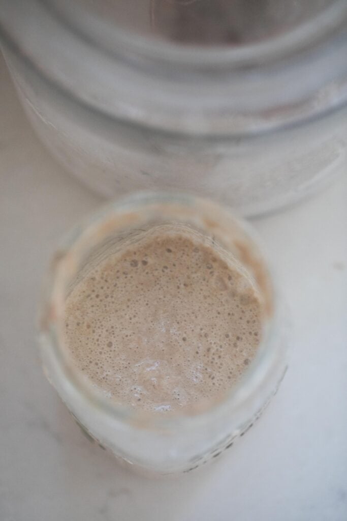 overhead photo of rye sourdough starter in a glass mason jar with another jar in the background