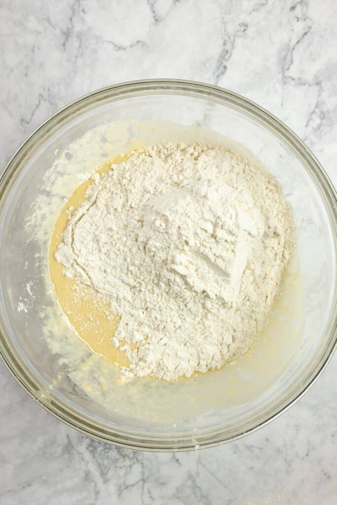 flour added to warm milk, yeast, and honey in a glass bowl