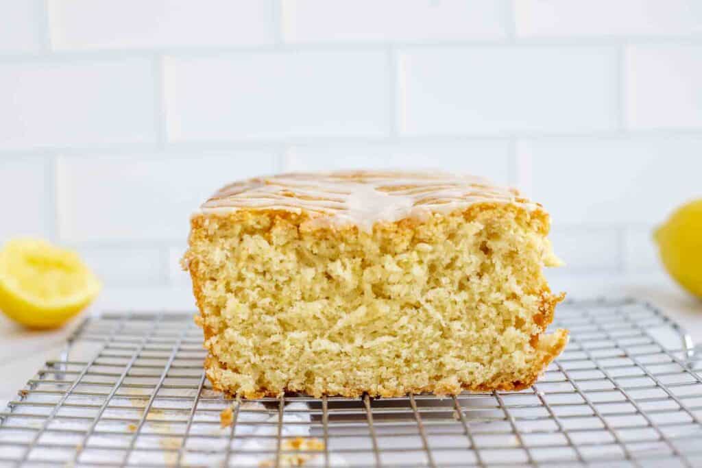 half of a loaf of lemon sourdough bread topped with lemon icing on a wire rack