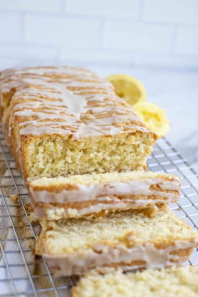 loaf of sourdough lemon discard bread with slices laying next to the loaf on a wire rack