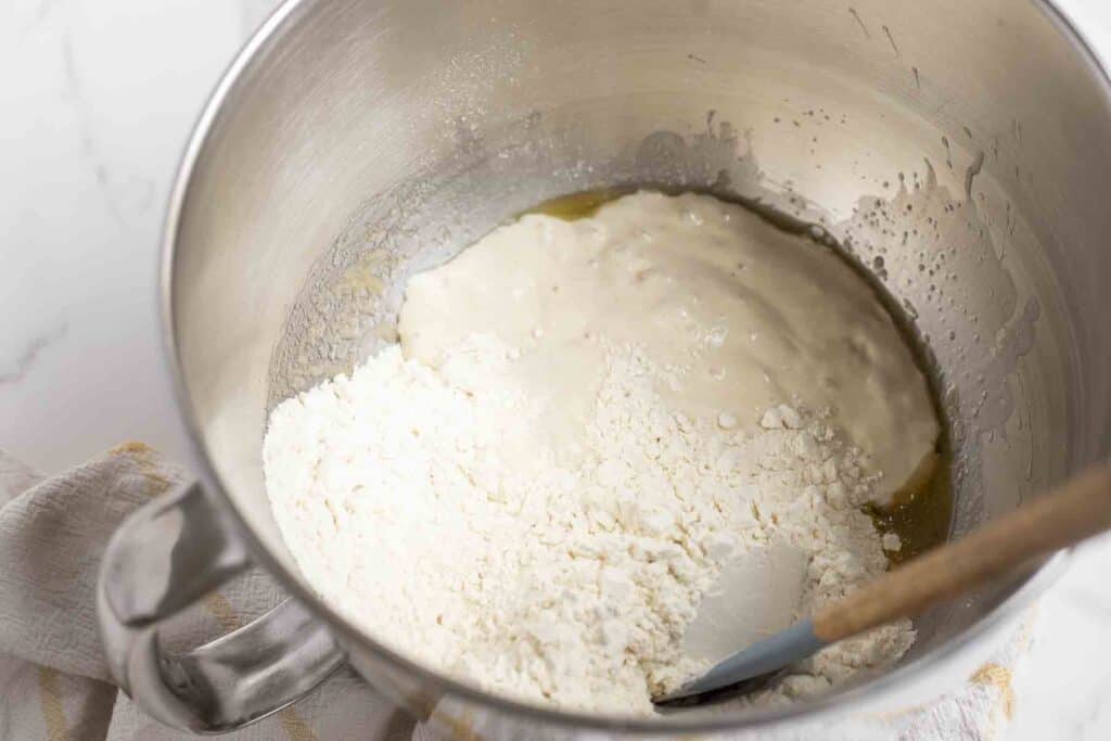 sourdough starter, flour, melted butter and more in a stainless bowl