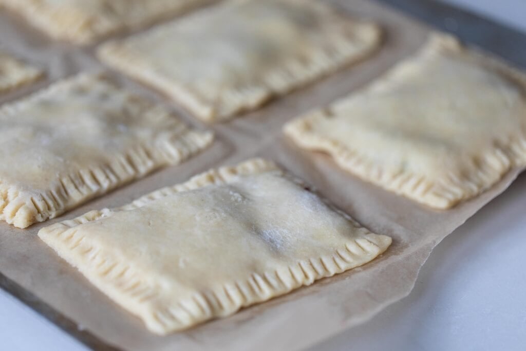 Sourdough poptarts on a parchment paper lined baking sheet ready for the oven