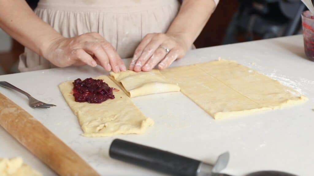 two hands folding over the top layer of dough for sourdough pop tarts