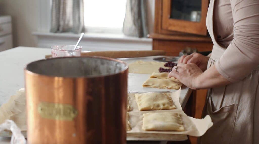 Woman transferring sourdough poptarts to parchment paper lined baking sheet