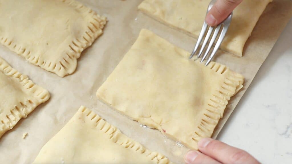 someone crimping the edges of unbaked sourdough pop tarts with a fork