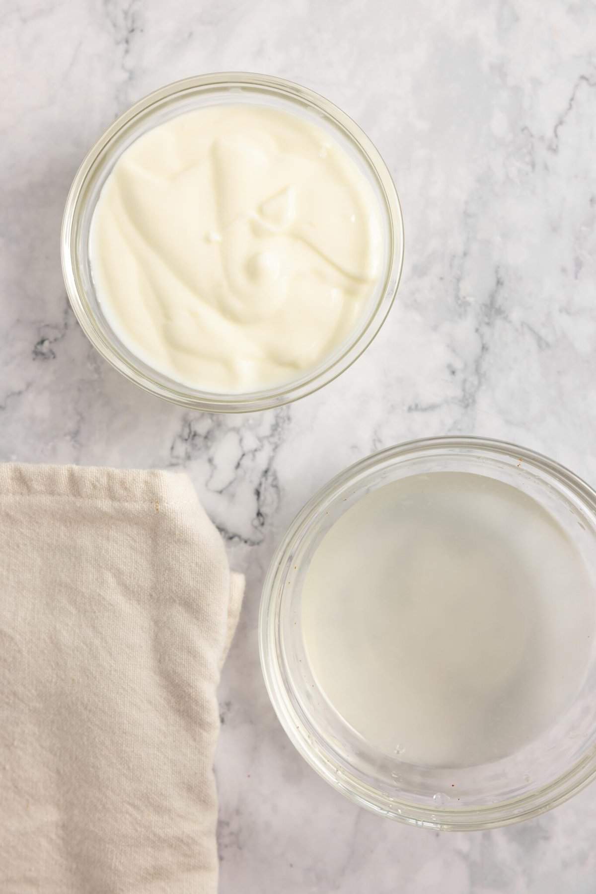 a jar of yogurt and a jar of whet with a towel to the left.