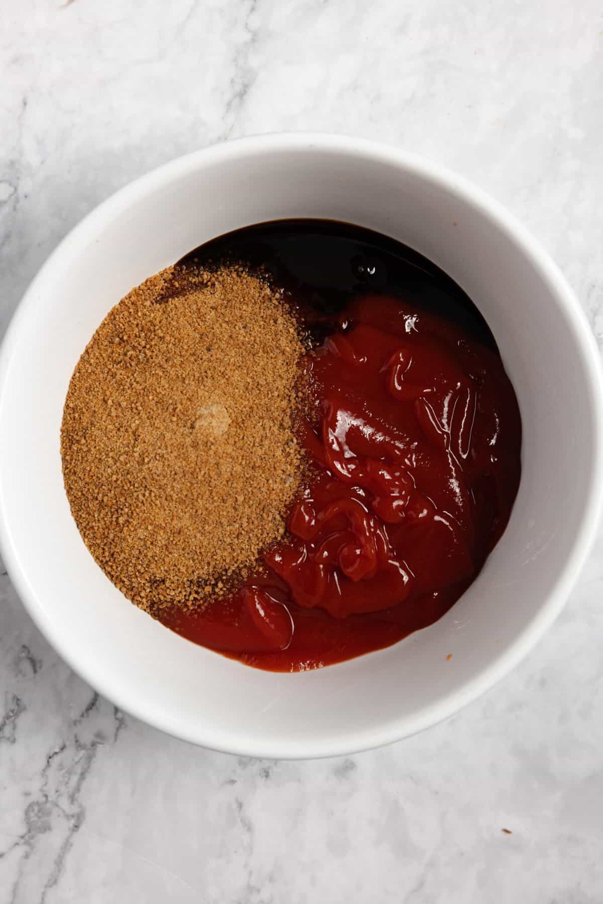 Ingredients for meatloaf glaze in a small white bowl on a white countertop