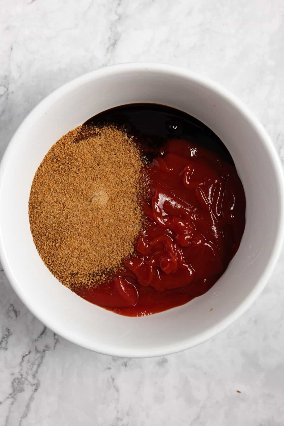 Ingredients for meatloaf glaze in a small white bowl on a white countertop