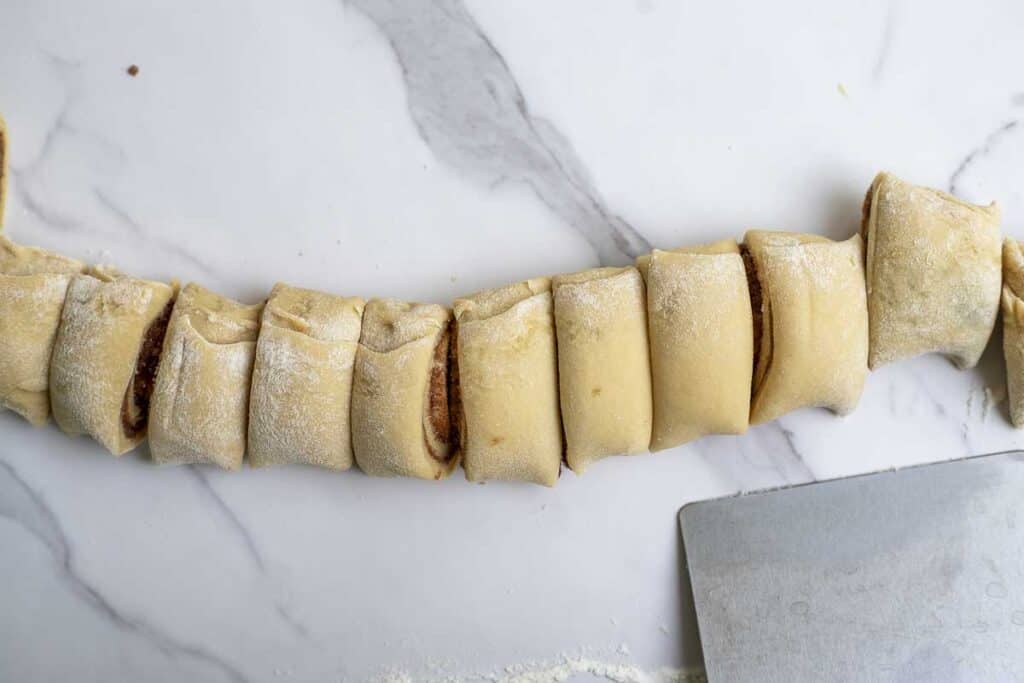 dough rolled up and sliced on a marble countertop