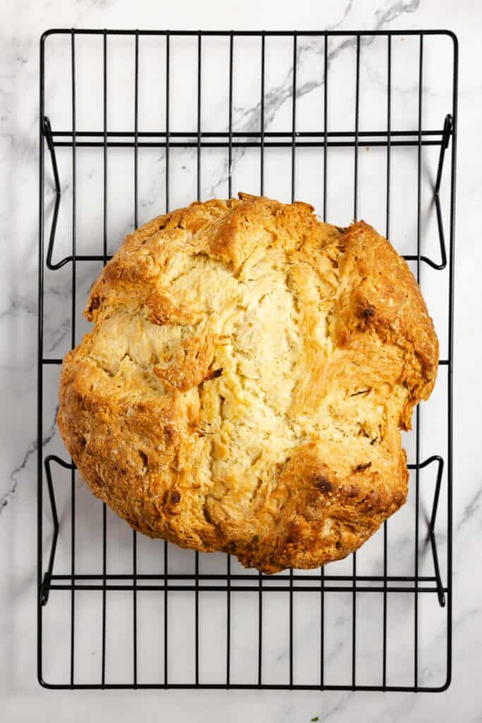 overhead photo of a loaf of sourdough Irish soda bread on a wire rack