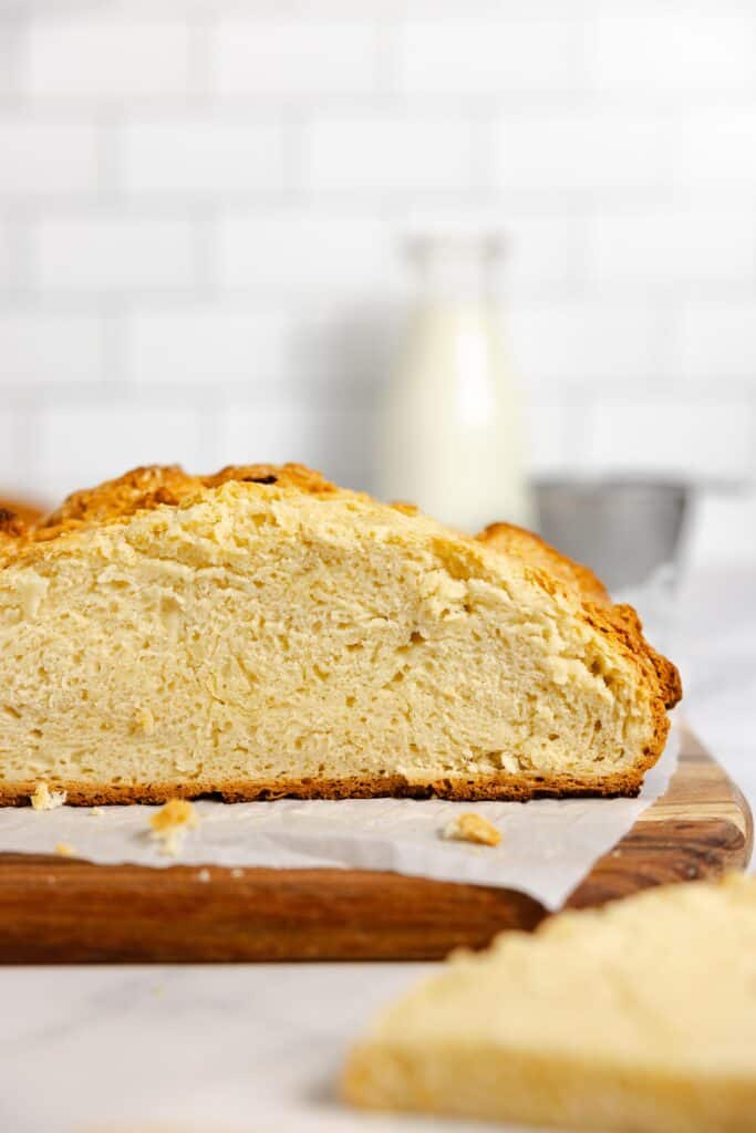 a side view of sourdough Irish bread with a slice taken off on a parchment lined cutting board