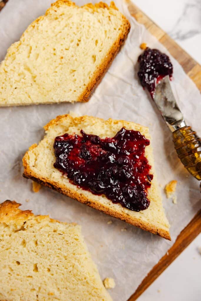 slices of sourdough Irish bread on parchment paper. One slice has blueberry jam on it.