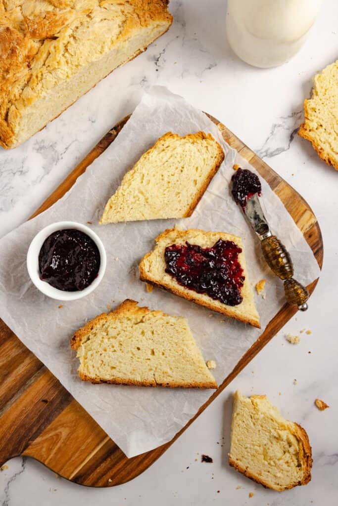 slices of sourdough soda bread on parchment paper. One slice has blueberry jam. 