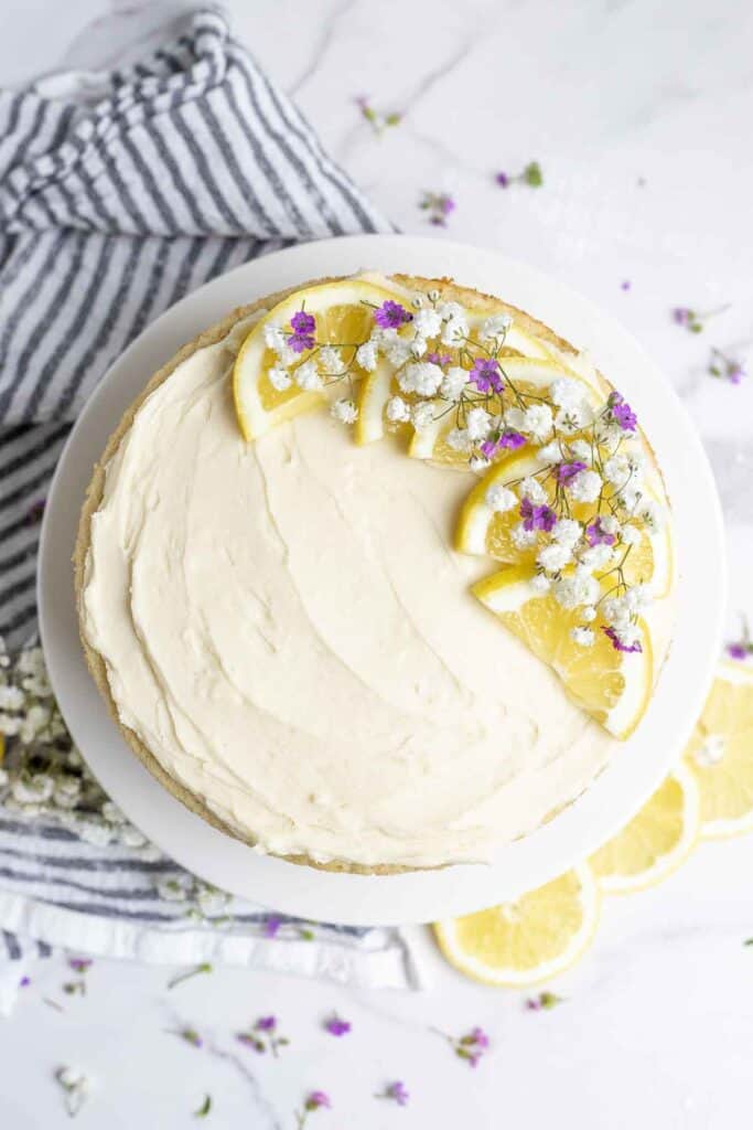The top of a layered lemon sourdough cake on a white countertop with a white and blue striped tea towel on the side.