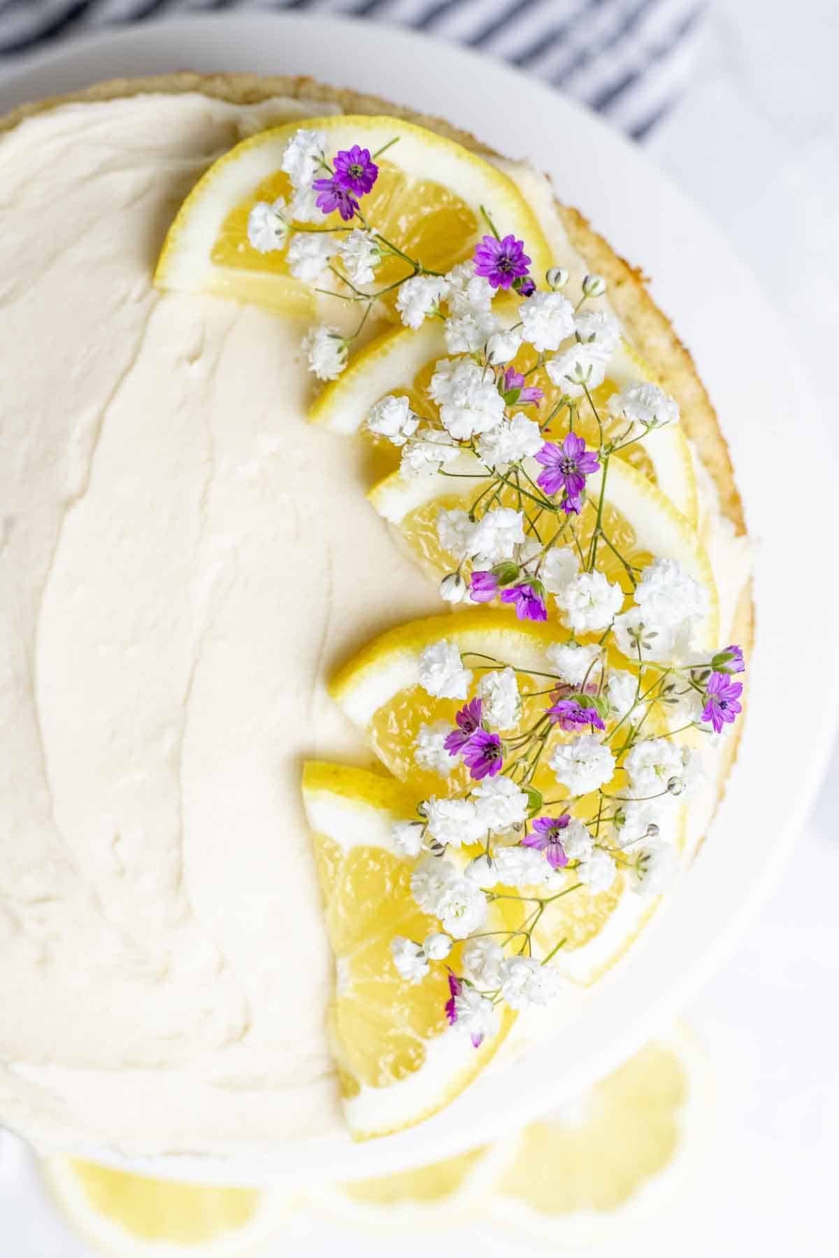 overhead photo of a lemon cake topped with lemon and fresh flowers