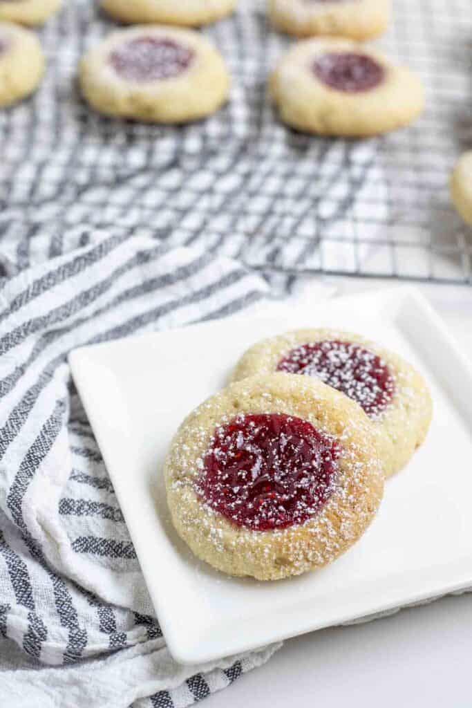 two thumbprint cookies on a whit plate on a white and black stripped towel