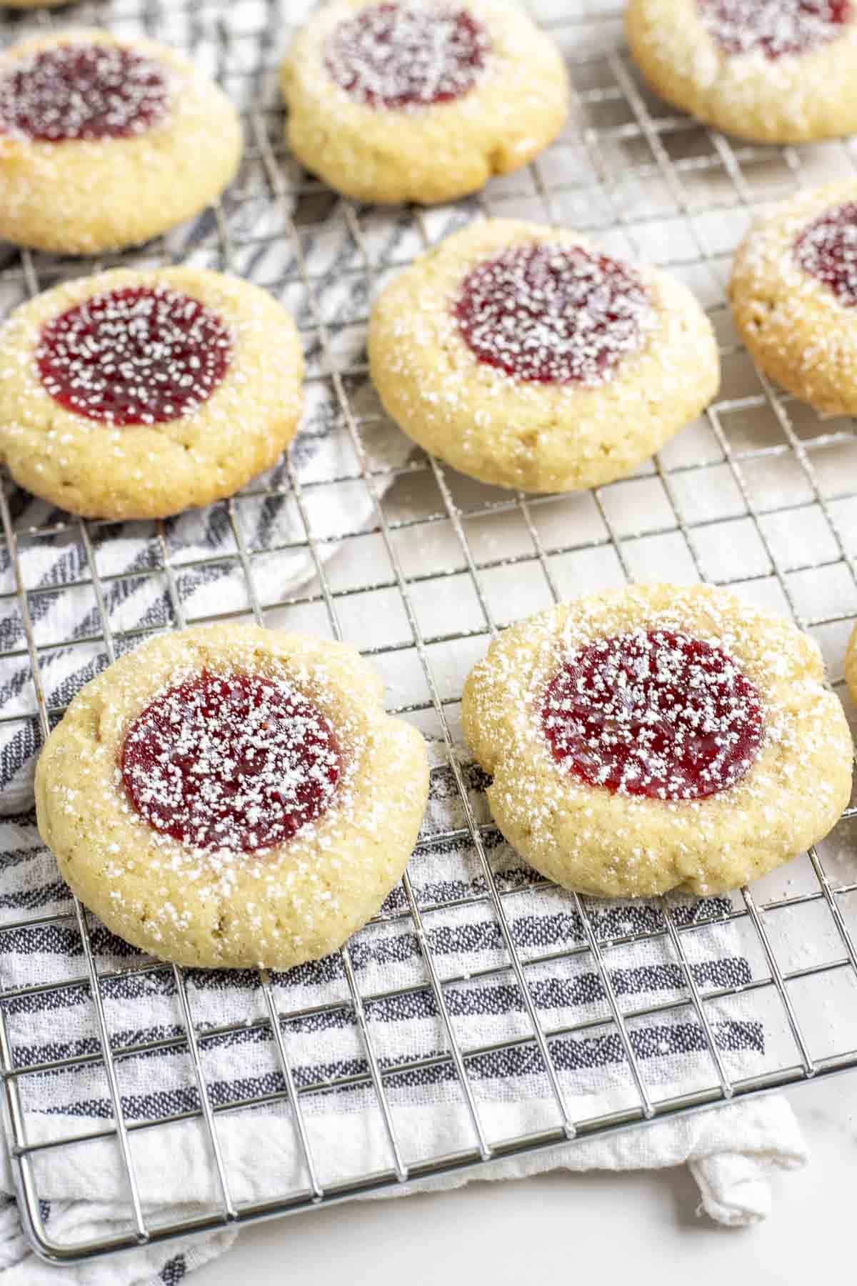 sourdough t thumbprint cookies on a wire rack on top of a black and white stripped towel