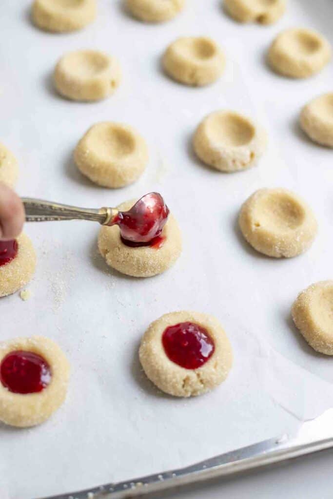 adding jam to cookie dough on parchment paper