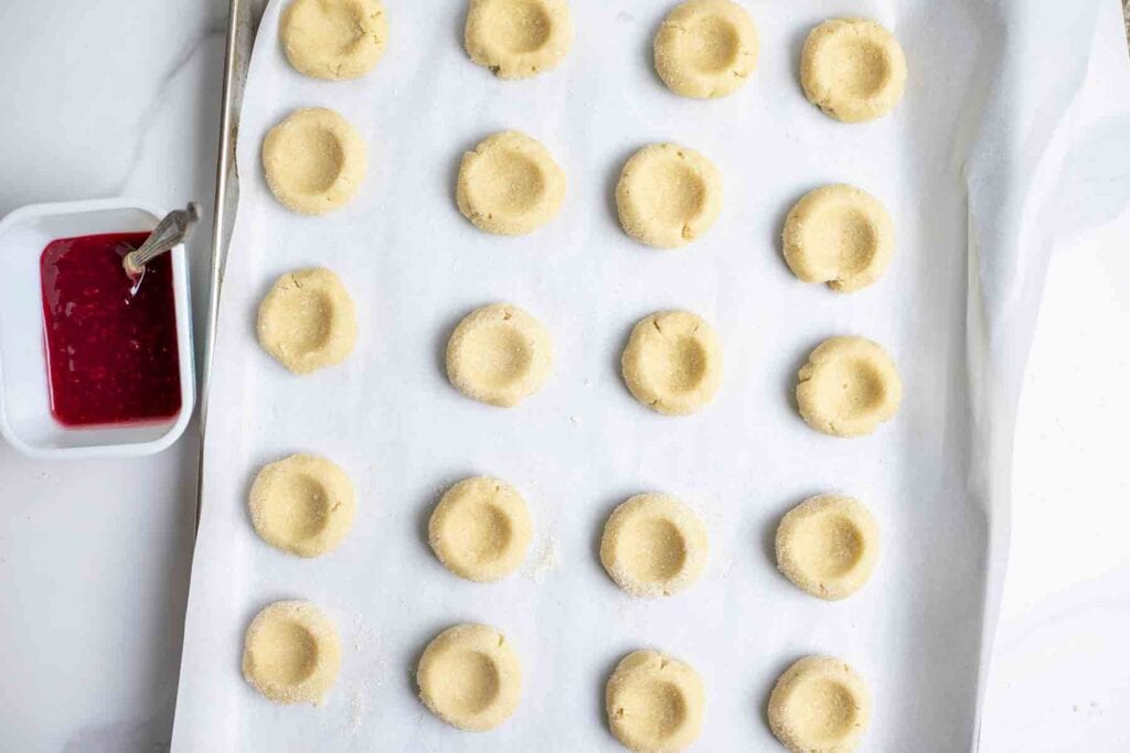 sugar cookie dough with wells in the middle on the dough on parchment paper