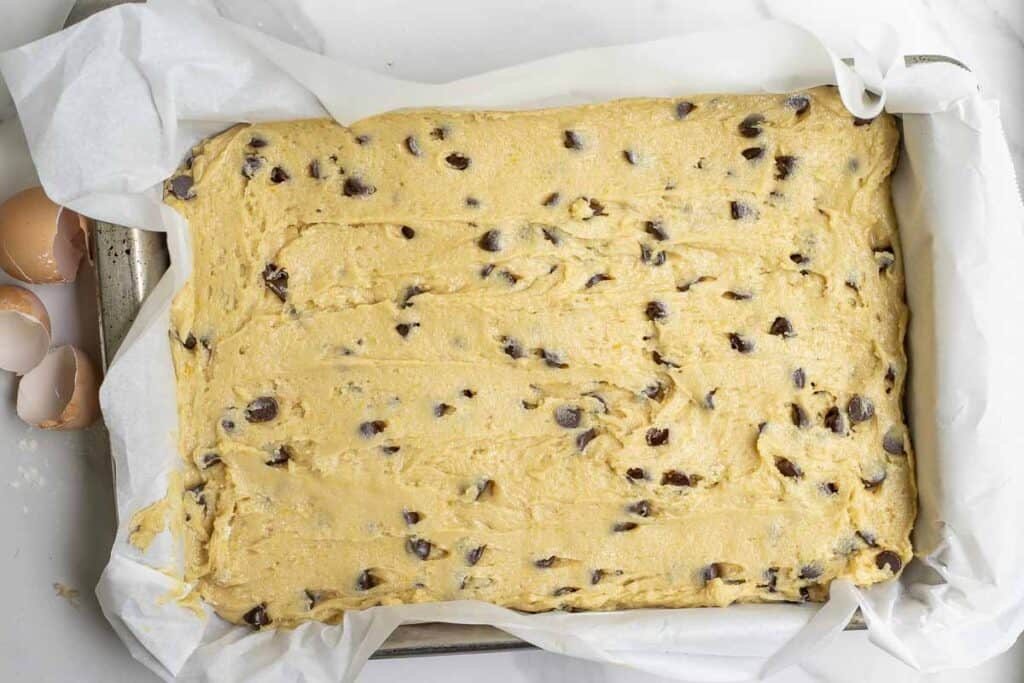 sourdough blondie batter in a parchment lined baking pan
