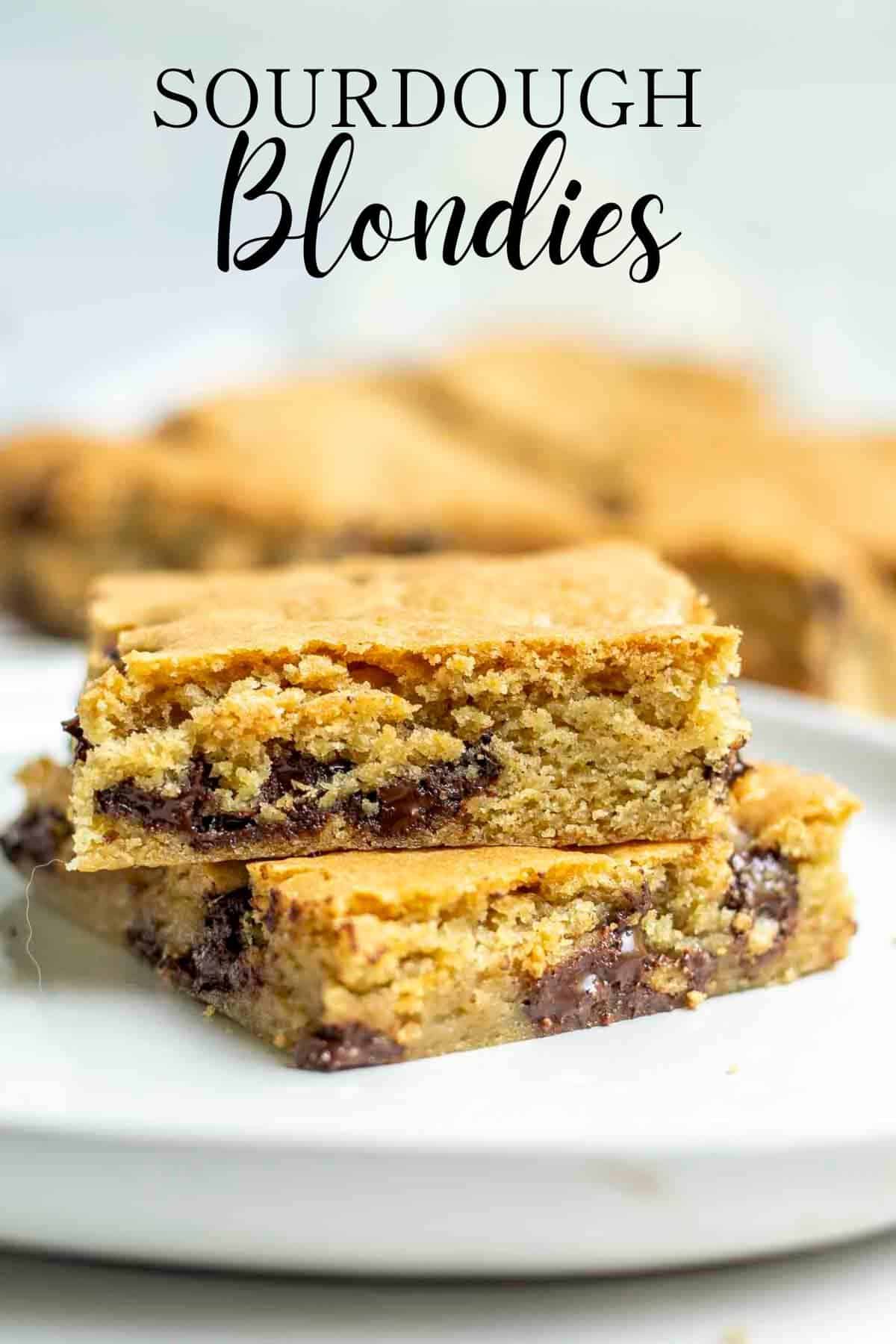 two slices sourdough blondies on a white plate with more blondies in the background.