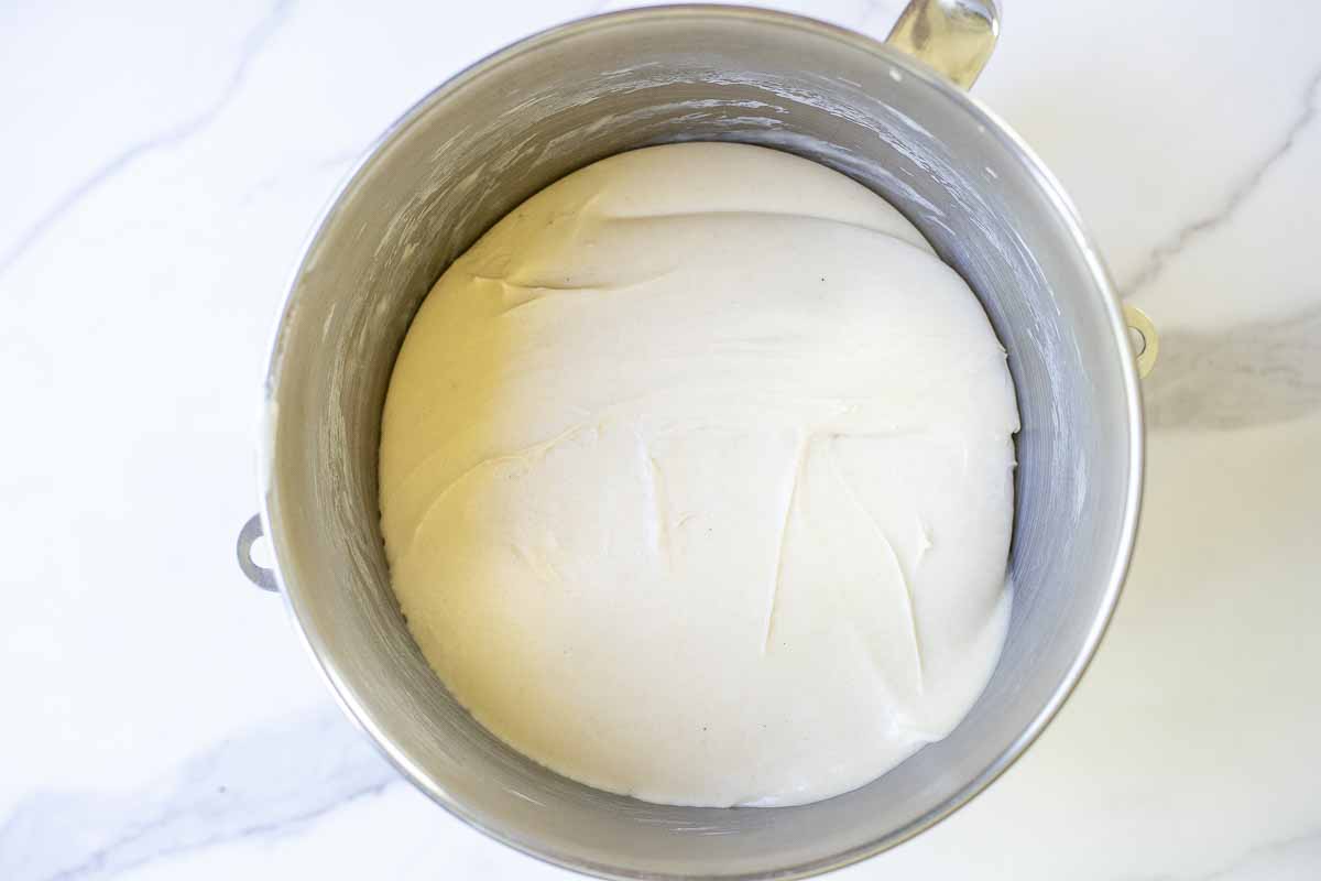 Sourdough ham and cheese roll dough in a stand mixer bowl fermented on a white countertop