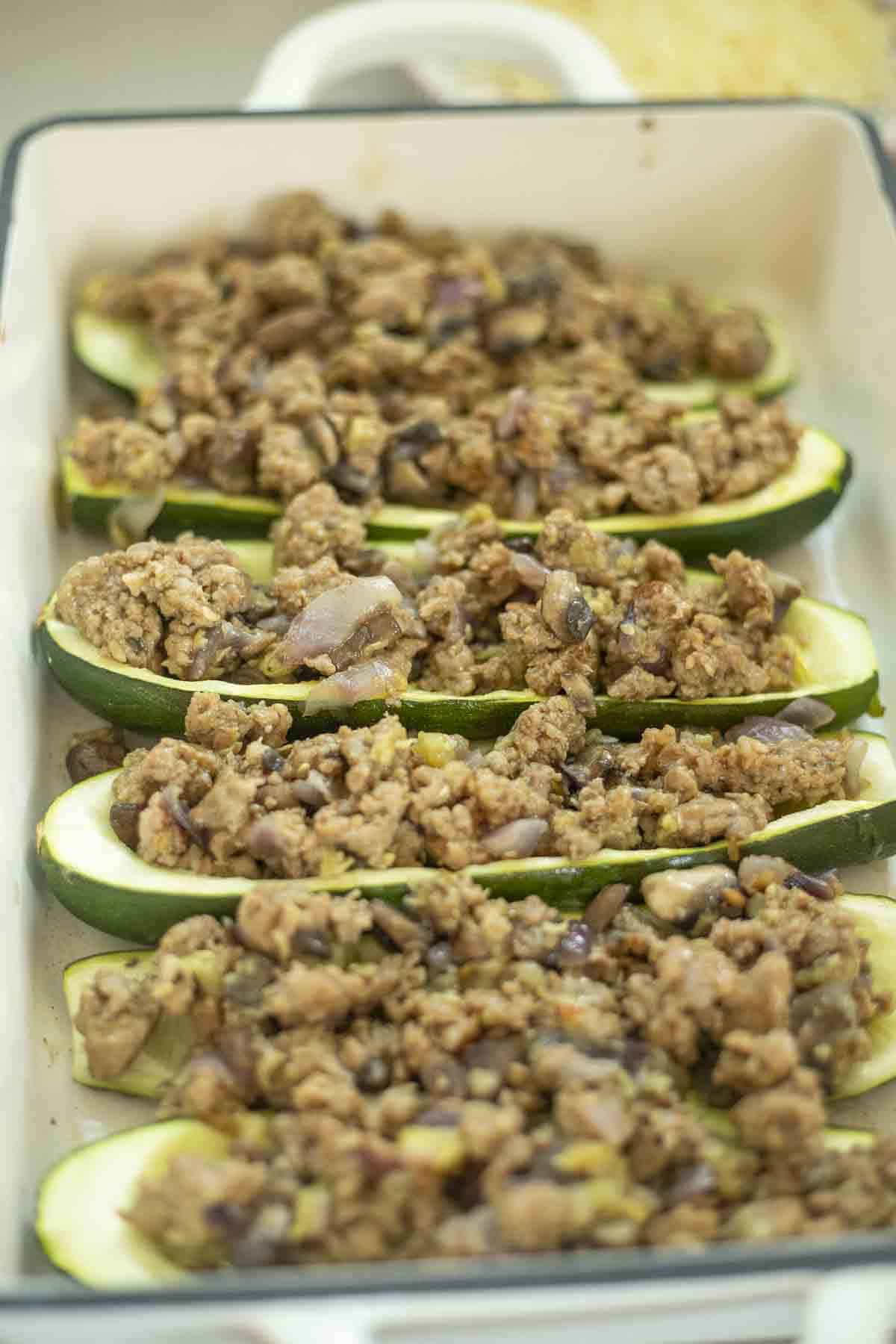 Sausage veggie mixture added to zucchini boats.
