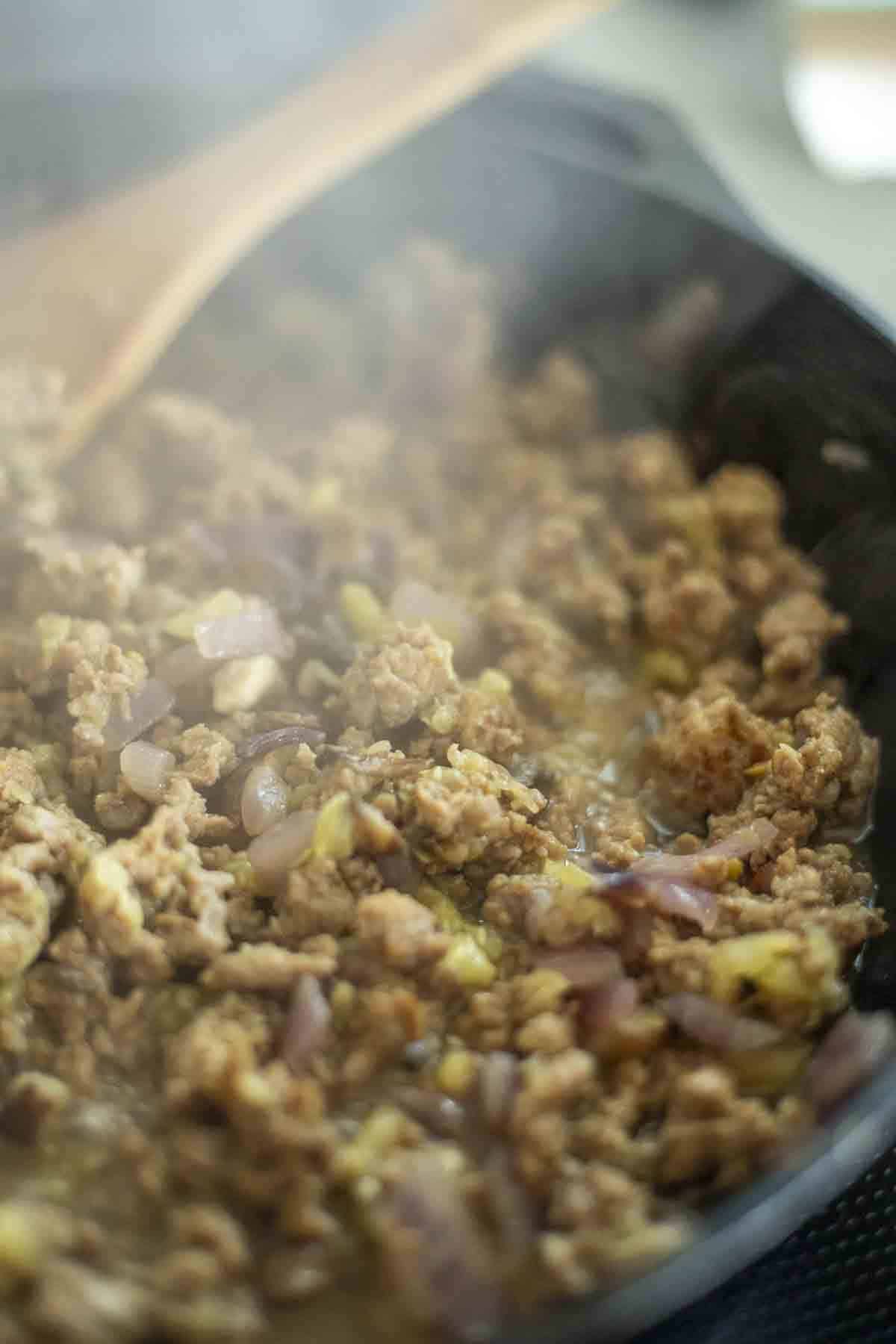 Sausage, mushrooms, onions, and zucchini in a cast iron skillet.