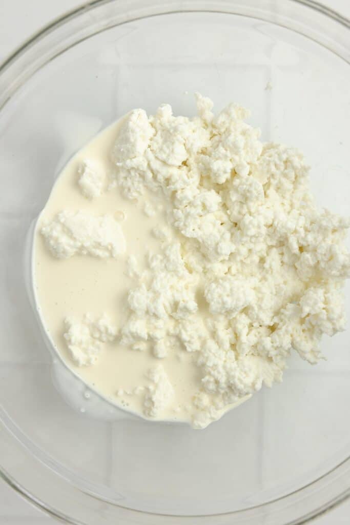 adding cream to curds in a bowl.