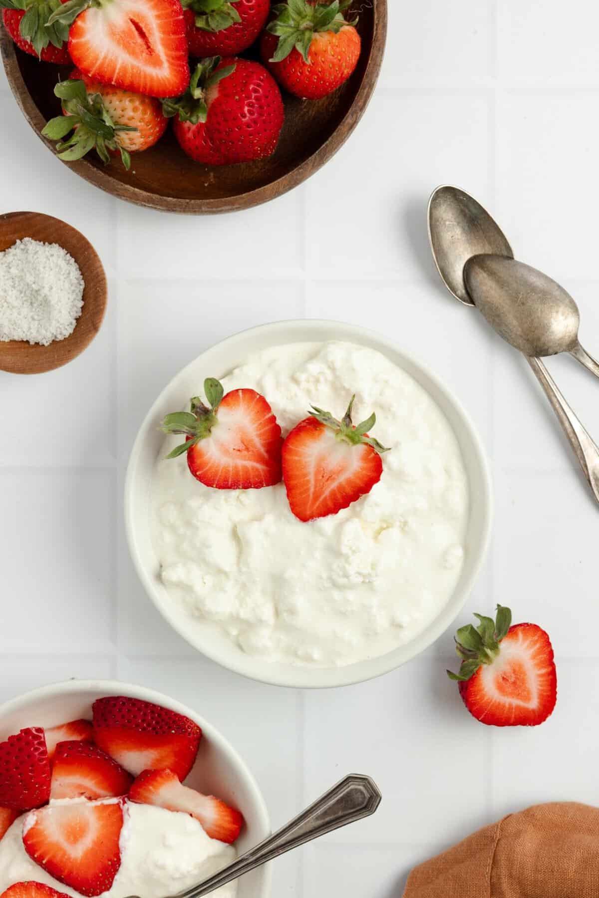 Overhead photo of homemade cottage cheese topped with strawberry slices on a countertop.