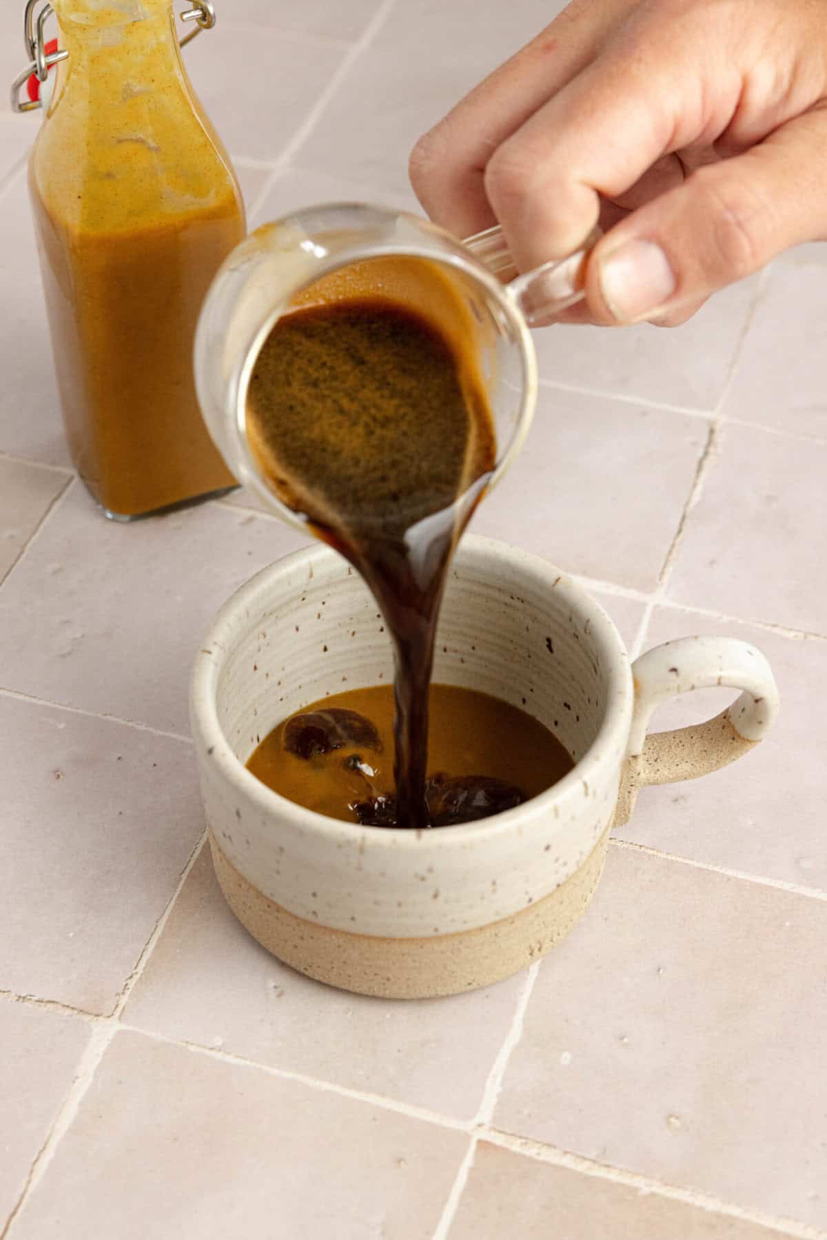 Espresso being poured into a white mug.