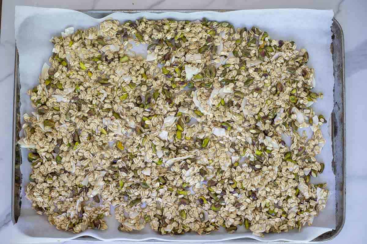 raw sourdough granola spread on a parchment lined baking sheet.