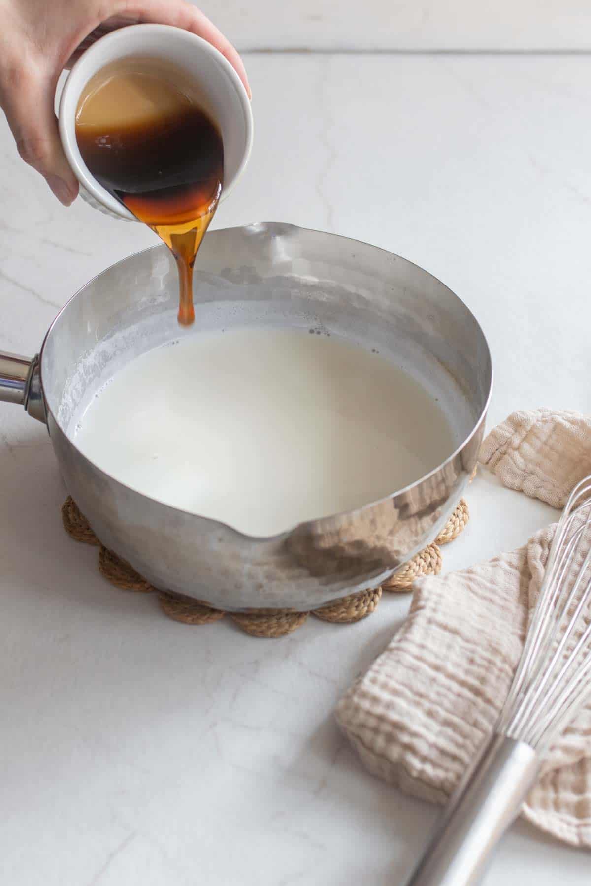 Maple syrup being poured into a saucepan of milk.