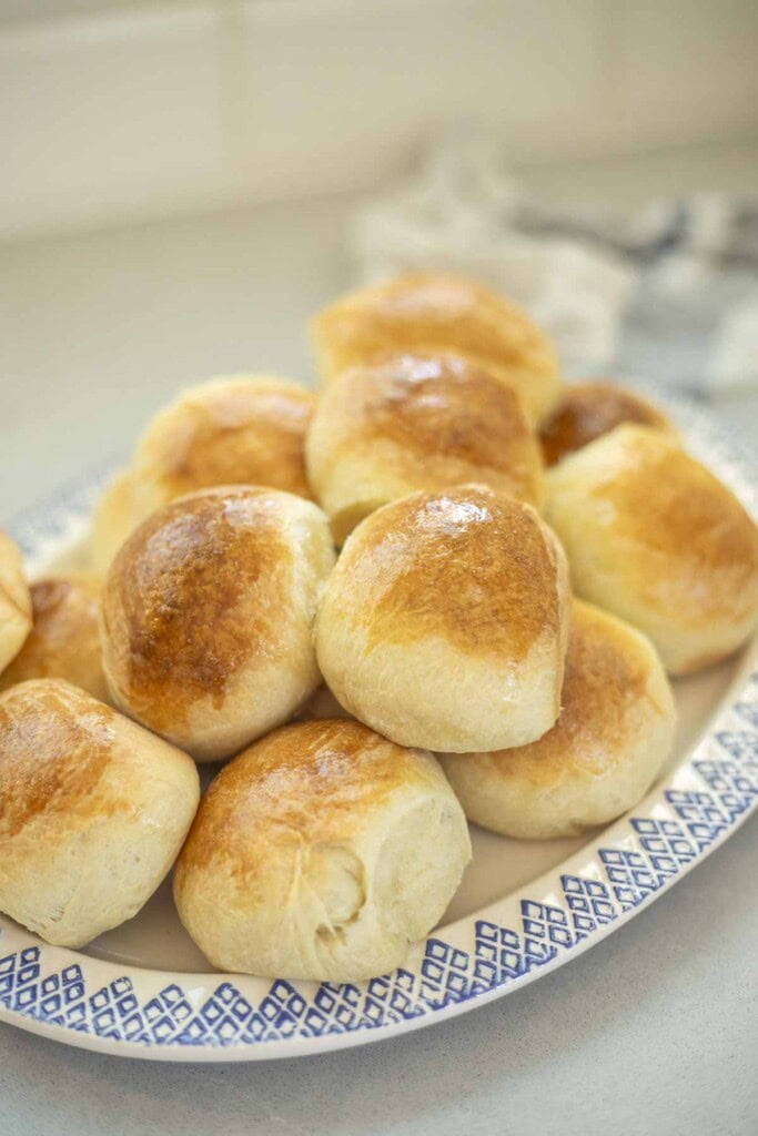 Sourdough brioche rolls stacked up on a blue and white plate.