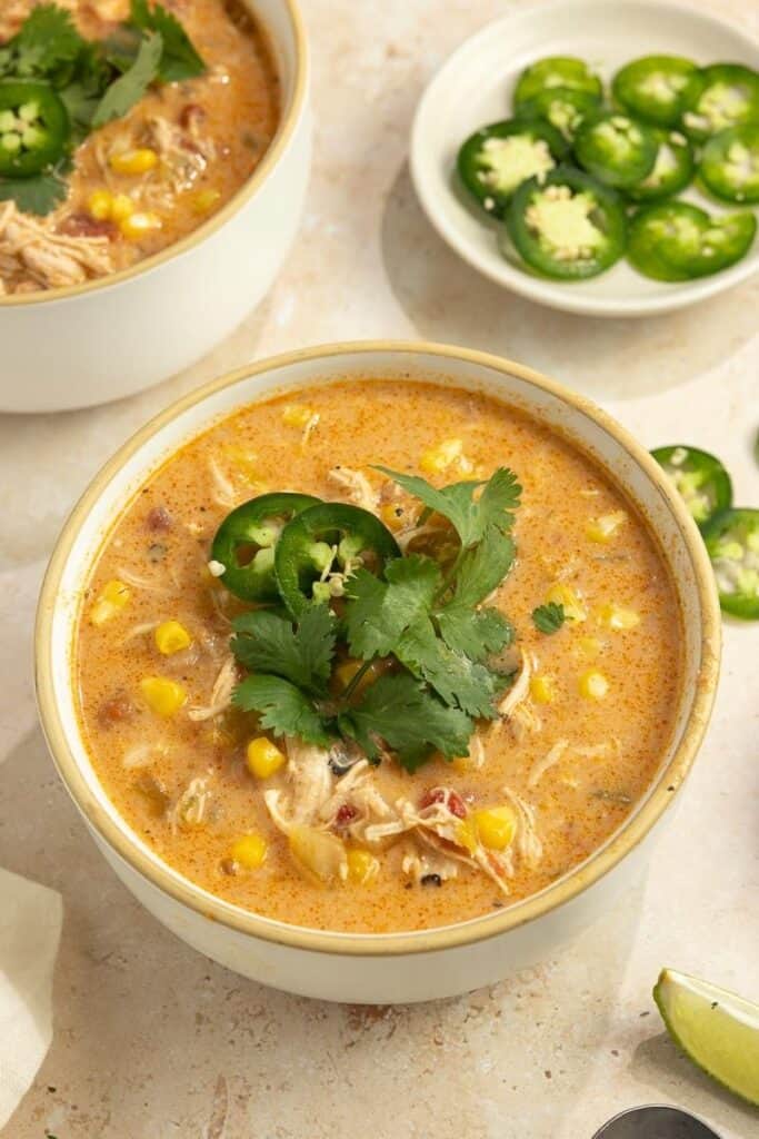 A bowl of white chicken chili topped with jalapeno slices.