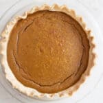A pumpkin pie on a white countertop.