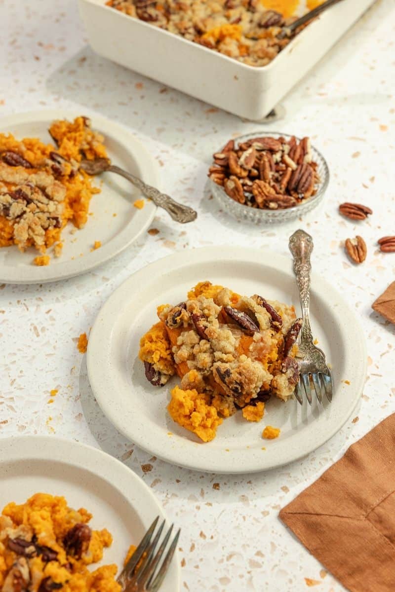 Three small white plates of sweet potato casserole on the kitchen counter.
