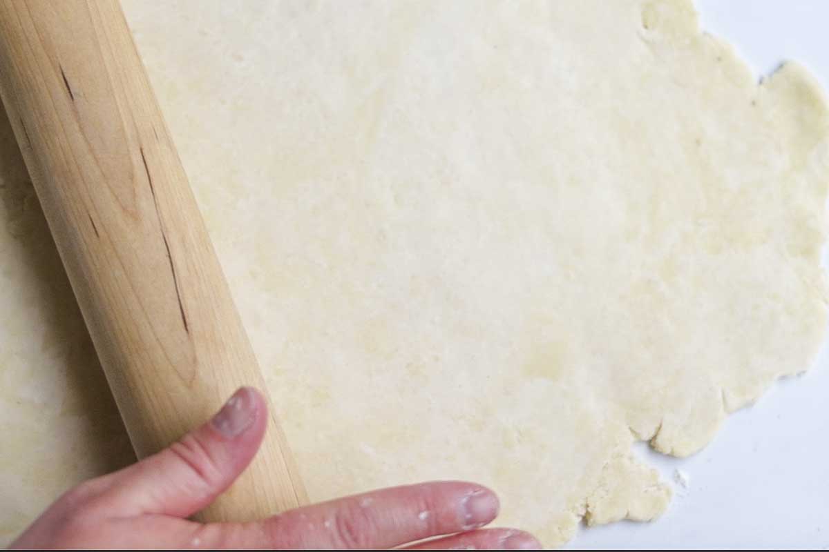 Pie dough rolled out in a circle with a rolling pin.