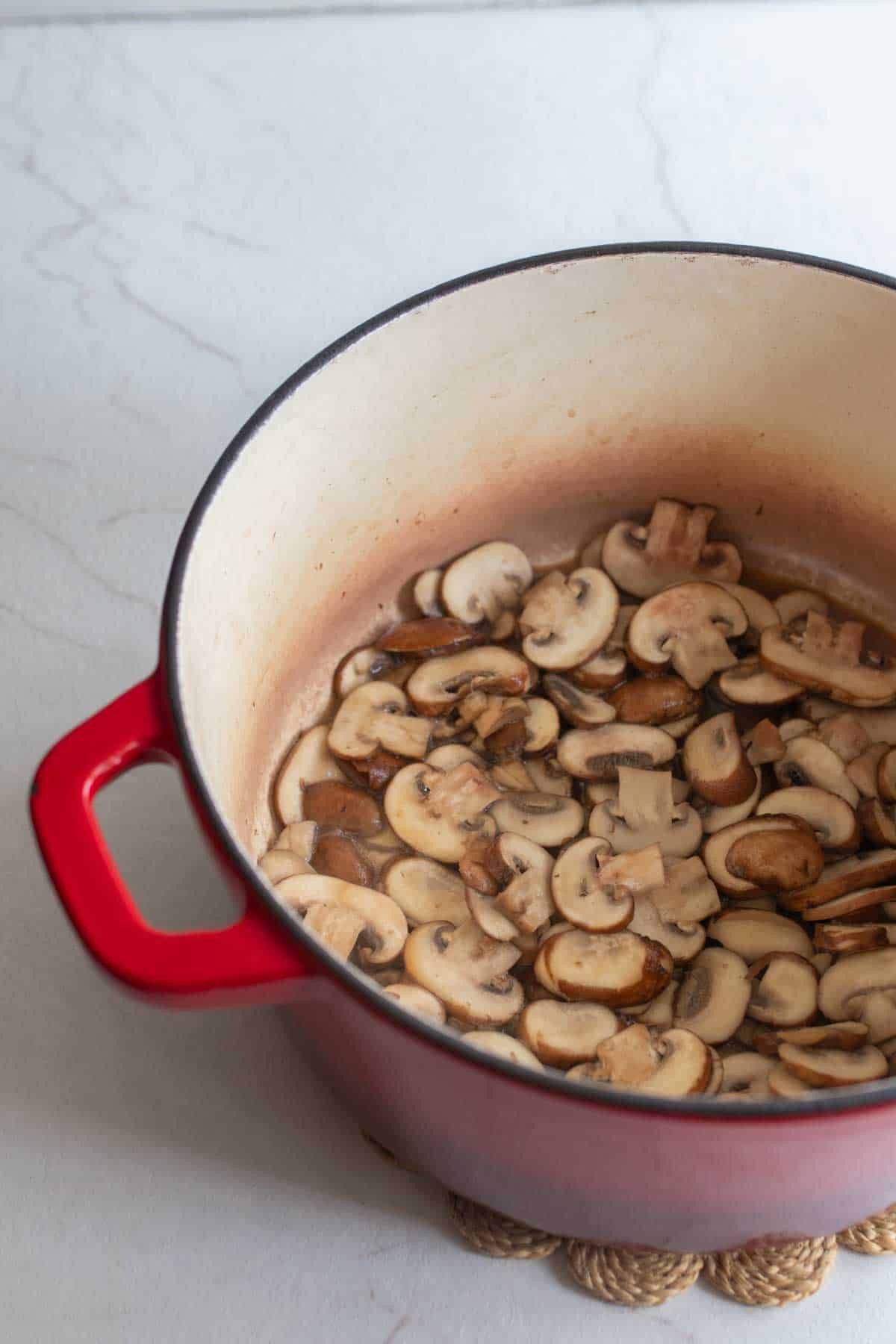 Sliced mushrooms in a large dutch oven.