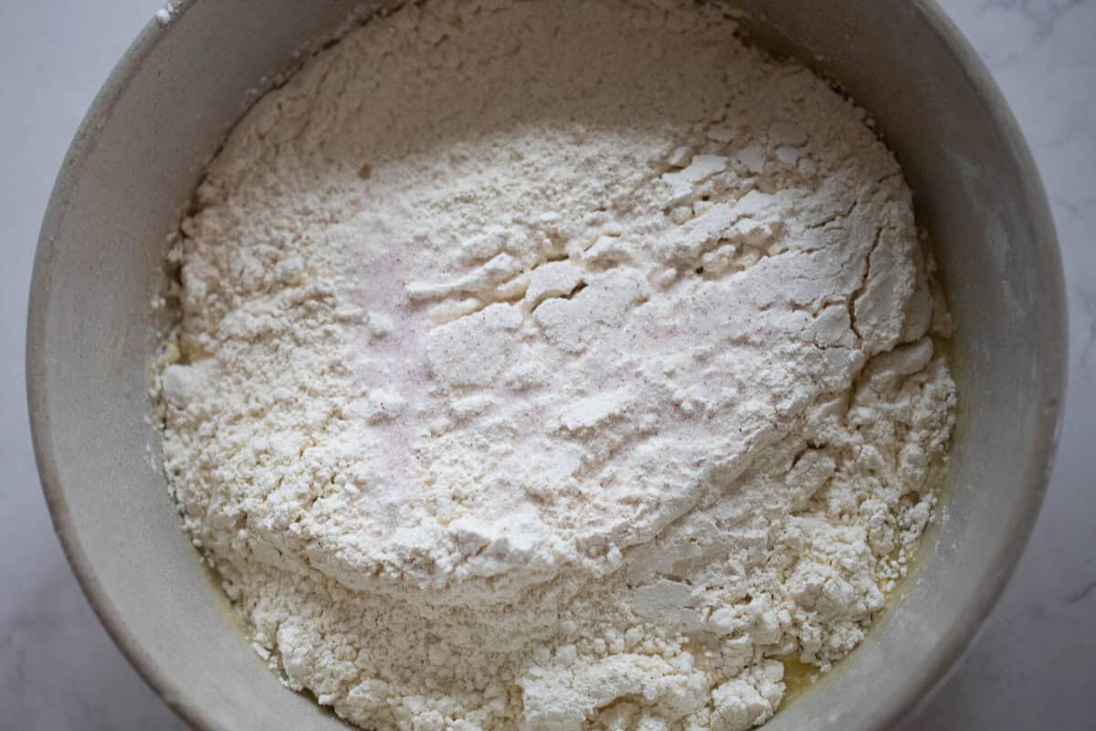 Adding flour to liquid ingredients in a bowl.