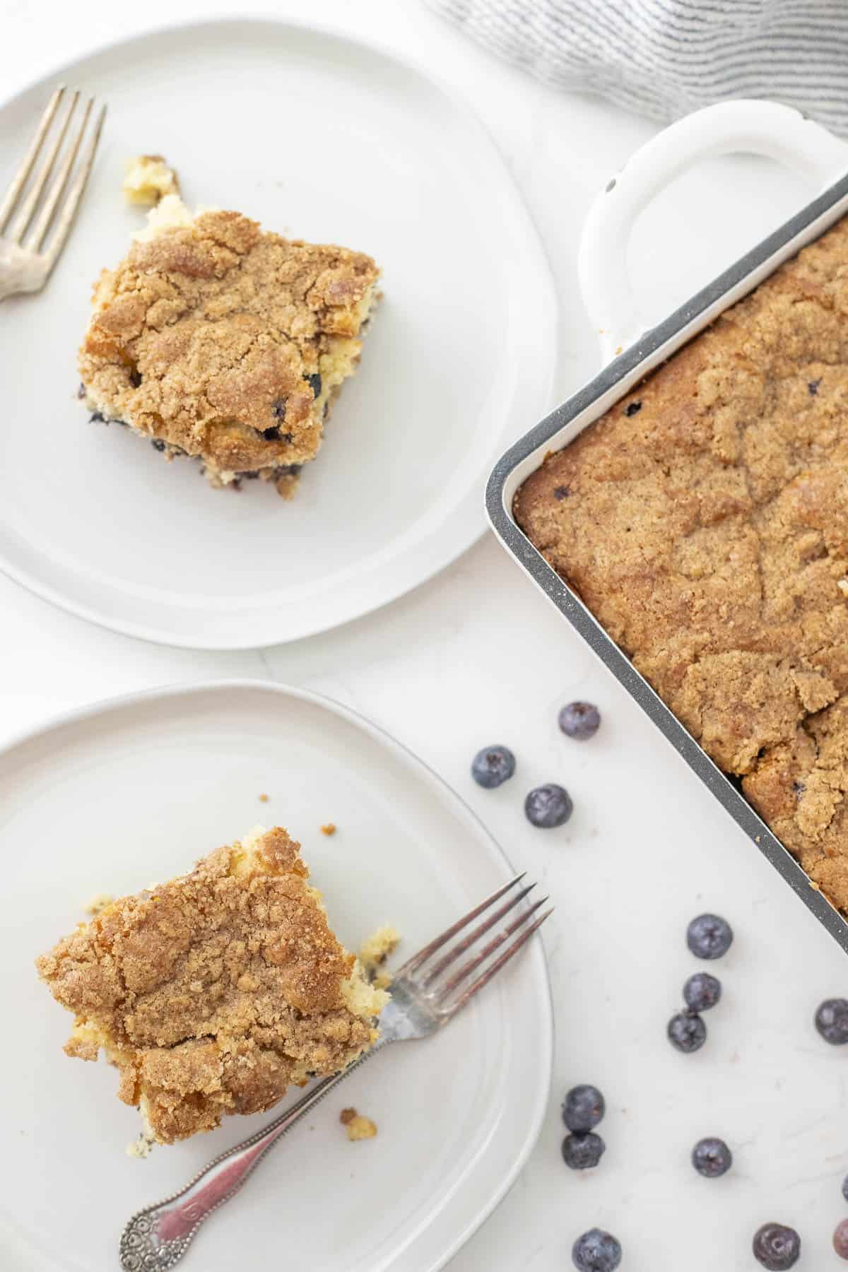 slice of coffee cake resting on top of baking dish of cake on a red and white towel