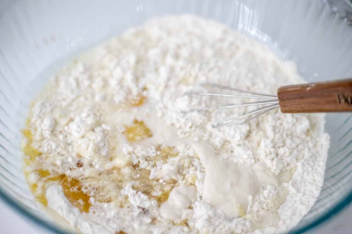 Dry ingredients and wet ingredients for sourdough discard pancakes in a large bowl with a whisk.