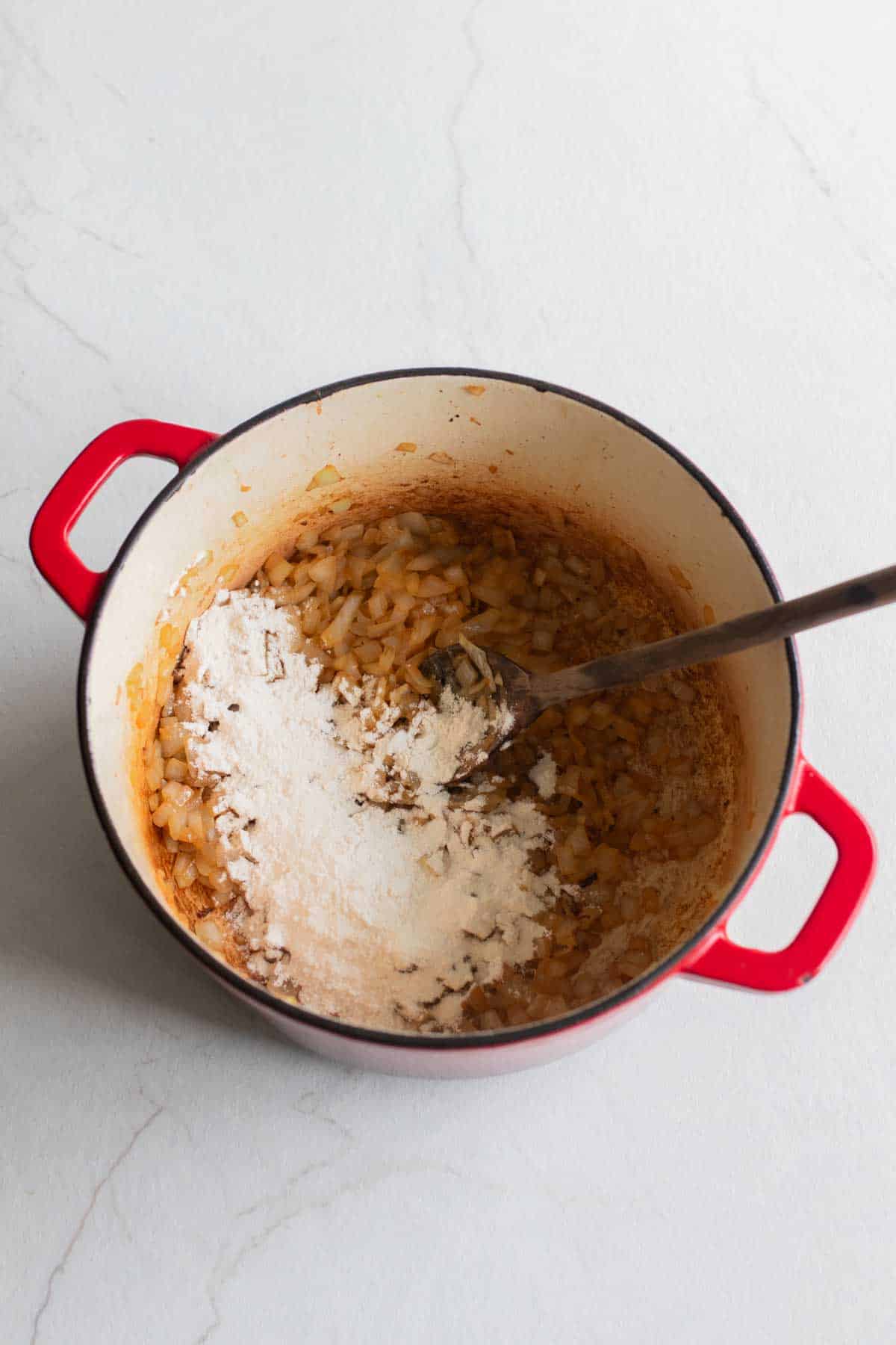 Flour added to onions in a Dutch oven.