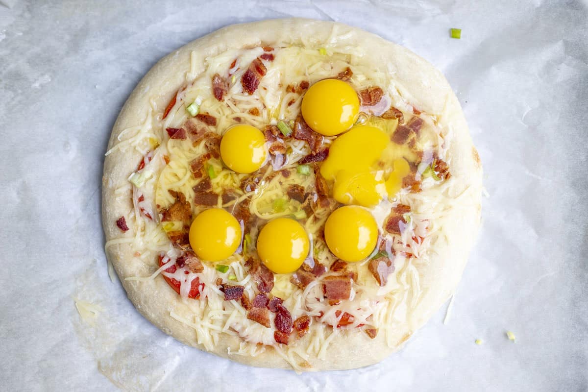 Raw eggs on a pizza.