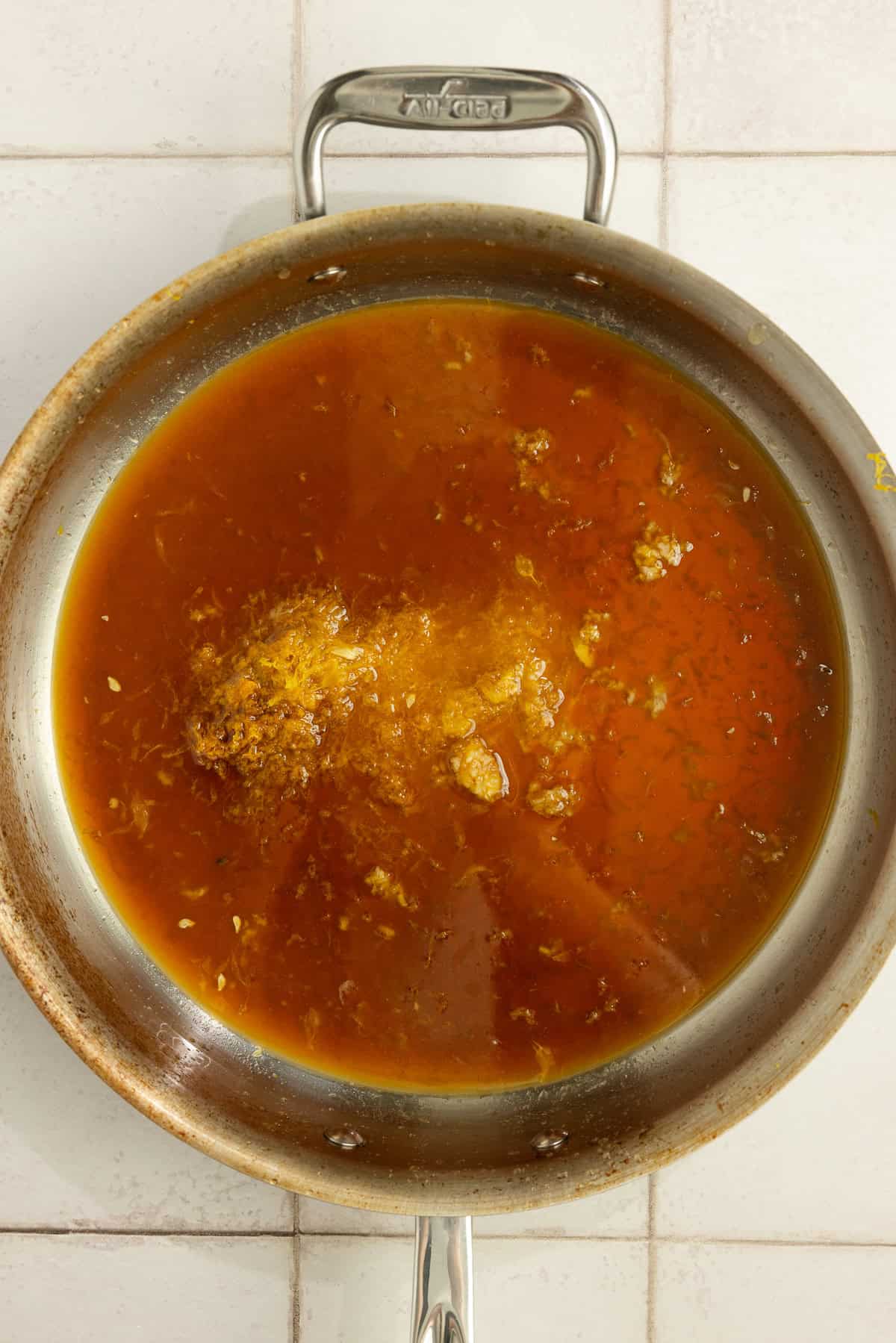 A saucepan with ingredients for an orange sauce.